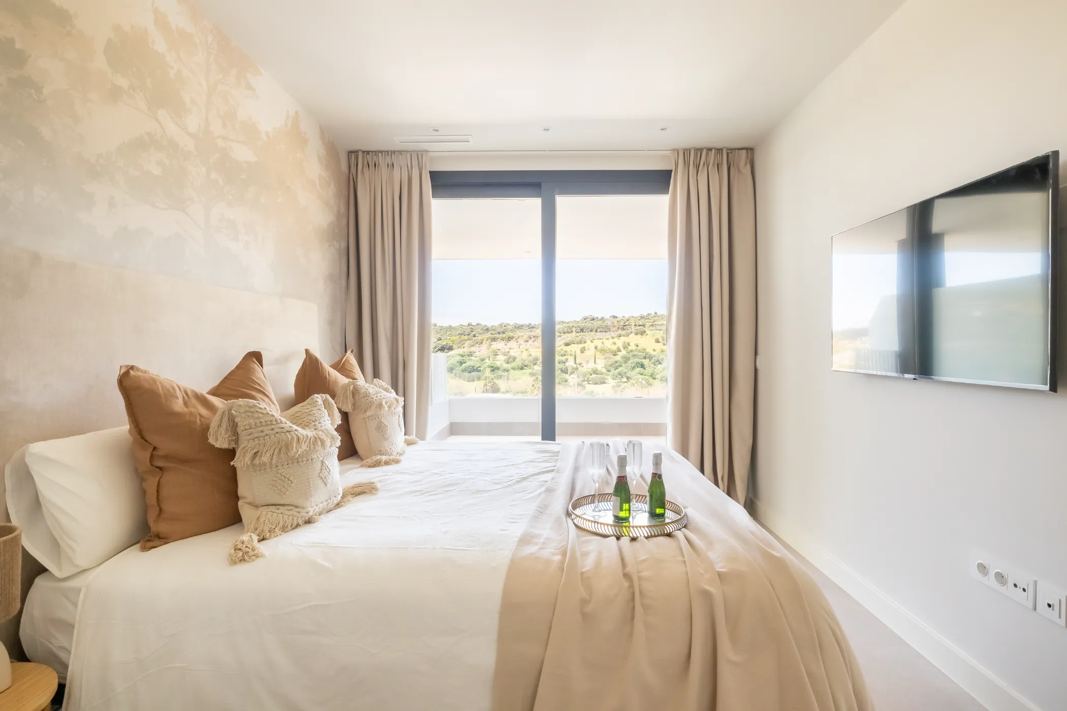 Dormitorio con acceso a terraza y cama de matrimonio preparada con cava de bienvenida.